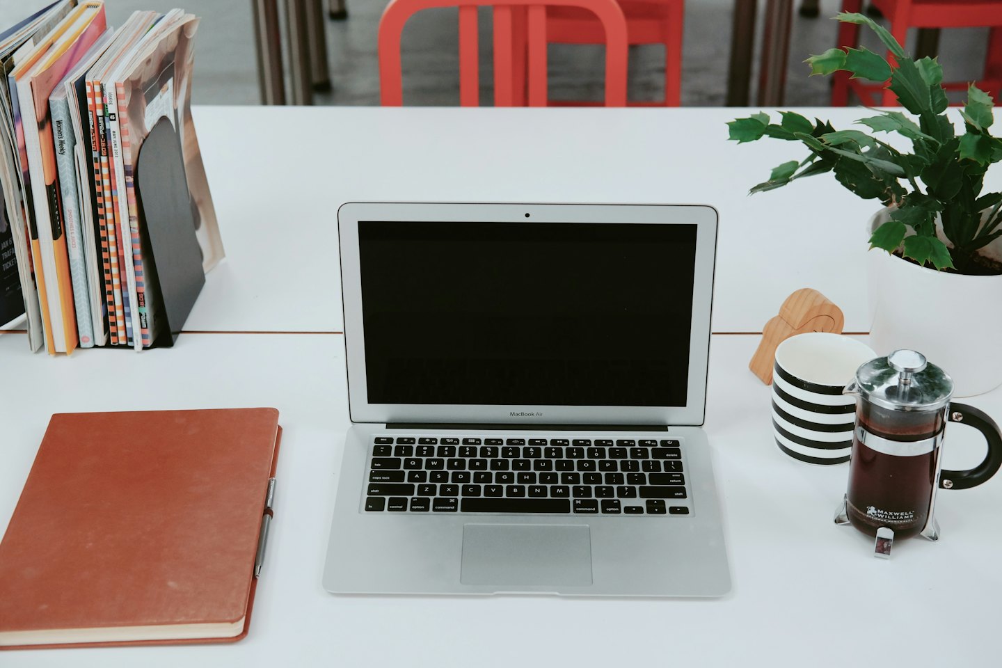 Laptop, plant, and coffee on a tidy white desk.