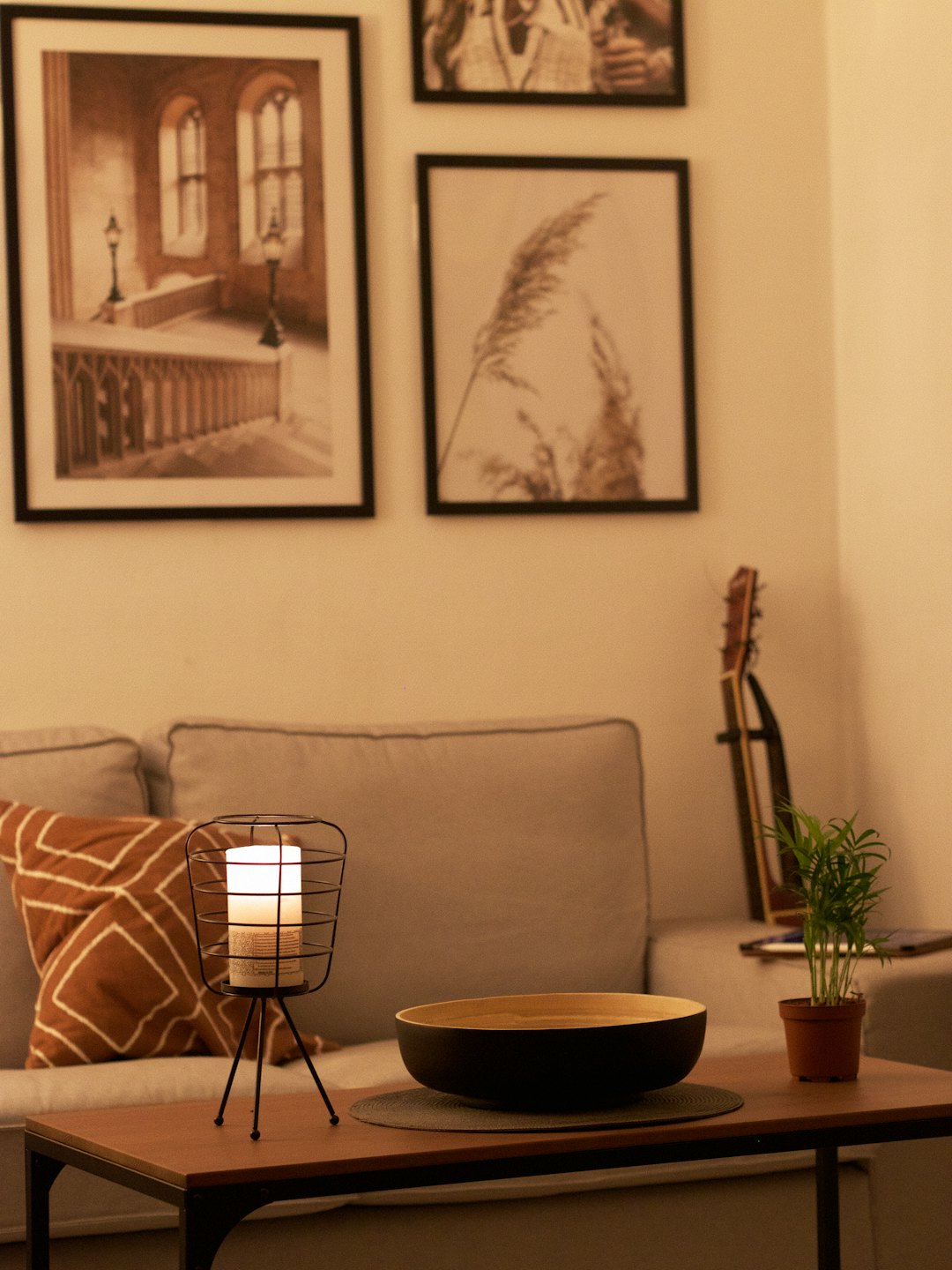 A wooden coffee table with a candle and plant sits before a sofa.